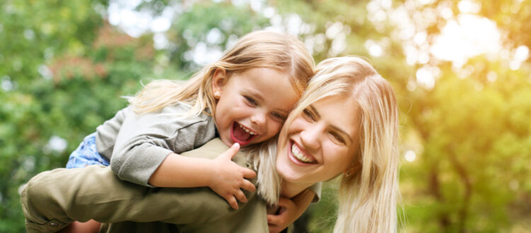 A mother giving her daughter a piggyback, and laughing together.