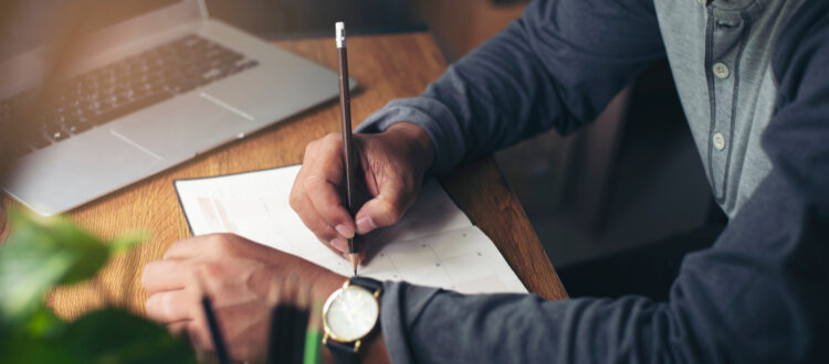 A man writing notes in a planner.