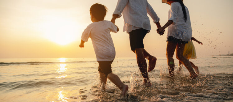 A family paddling in the sea at a beach.