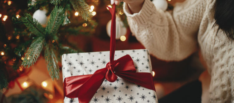 A woman unwrapping a Christmas gift.