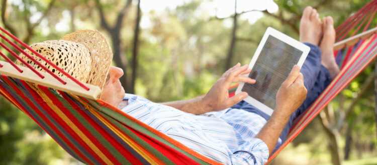 A man in a hammock using a tablet.