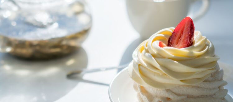 A cream cake on a table with a cup of tea.