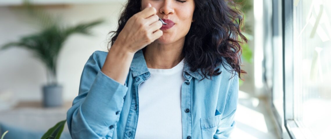 A woman eating a pot of yoghurt.