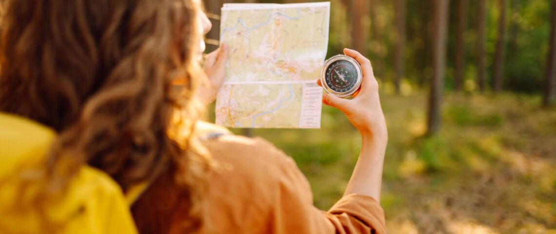 A young woman hiking and using a compass.