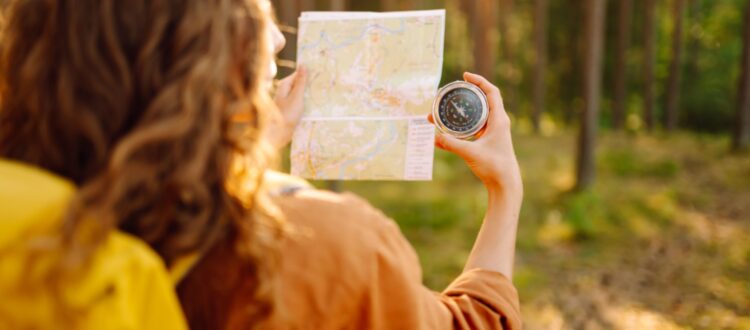 A young woman hiking and using a compass.