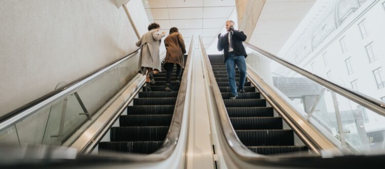 People using escalators in an office building.