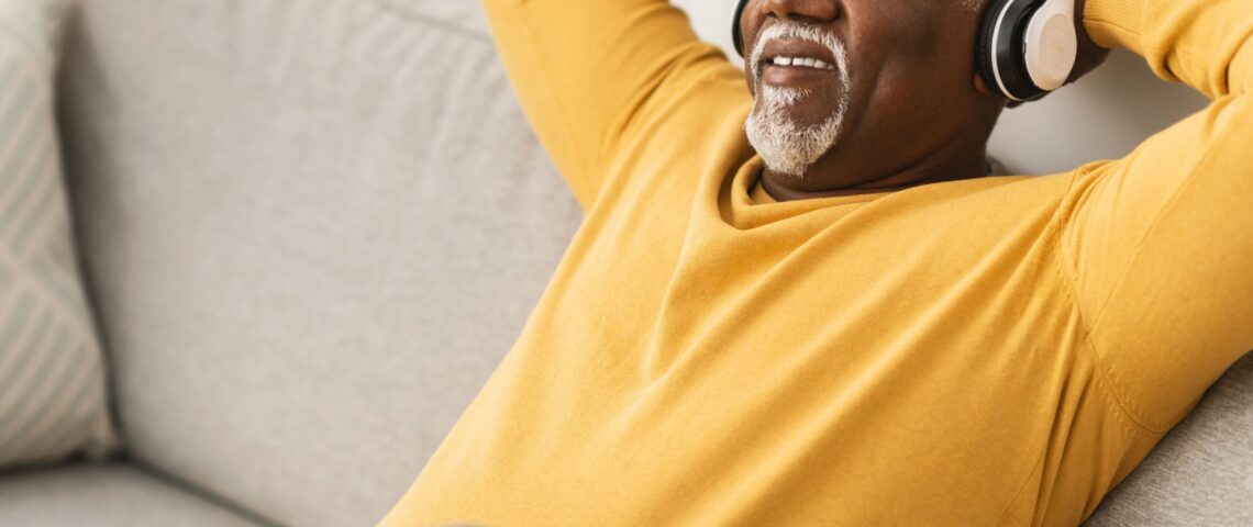 A man relaxing on a sofa with his hands behind his head.