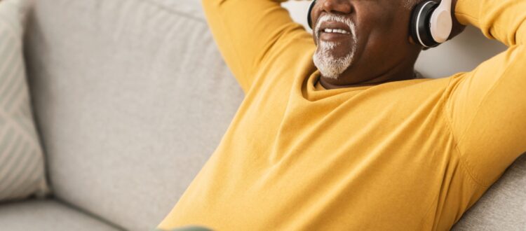 A man relaxing on a sofa with his hands behind his head.