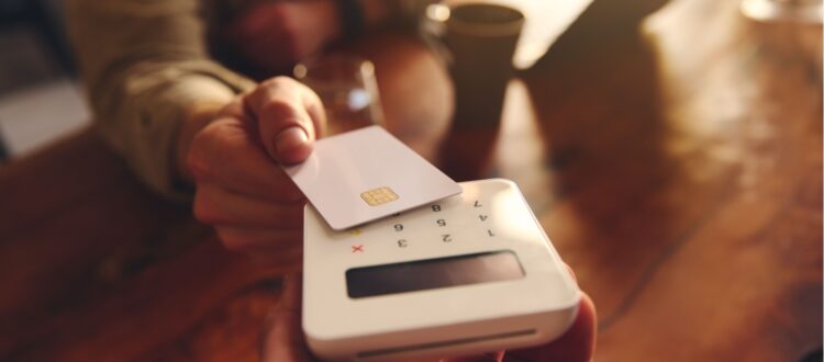 A person using their debit card to pay in a café.