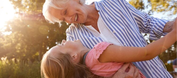 A grandmother playing with her granddaughter outside.