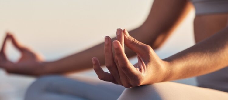 A woman sitting in the lotus position mediating.