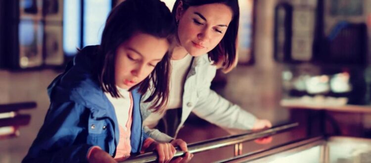 A mother and daughter viewing a museum exhibit.