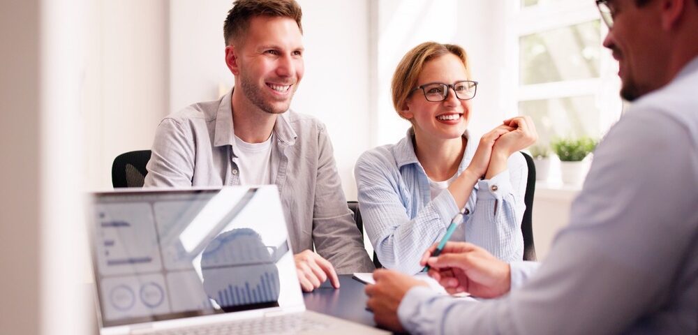 A couple happily talking with their financial planner.