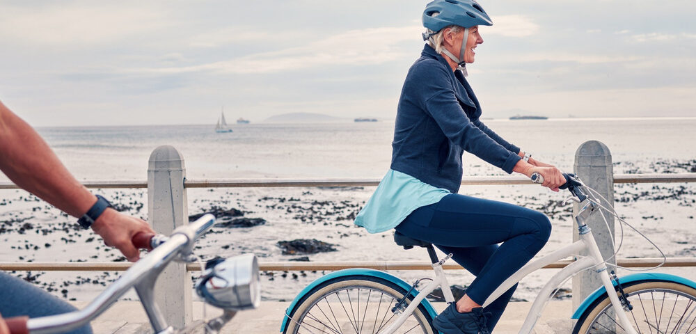 A woman cycling along a beachfront.