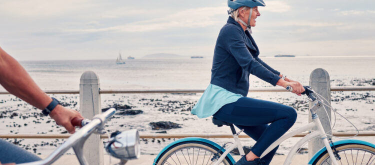 A woman cycling along a beachfront.