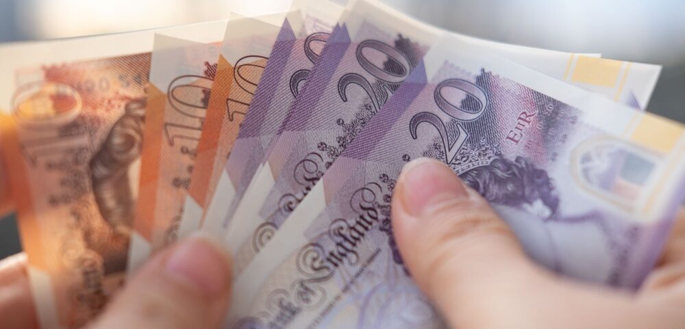 A person holding UK bank notes.