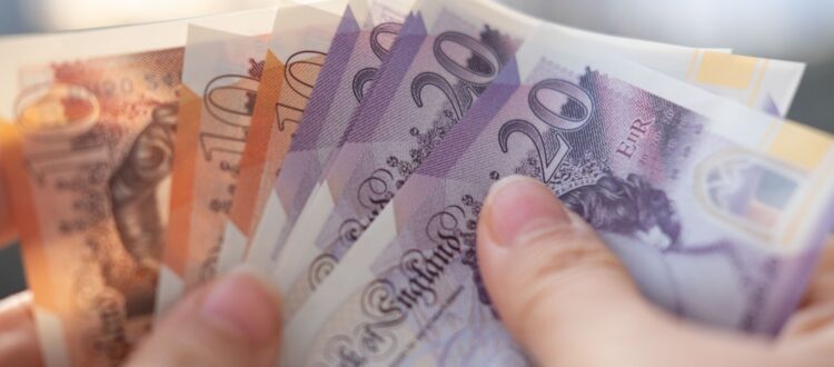 A person holding UK bank notes.